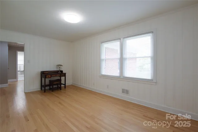 an empty room with piano table and windows