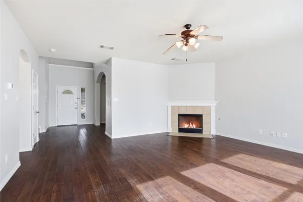 a view of an empty room with wooden floor fireplace and a window