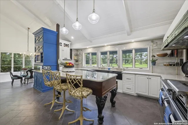 a dining hall with stainless steel appliances granite countertop a sink a stove a dining table and chairs with wooden floor