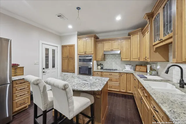 a kitchen with granite countertop kitchen island stainless steel appliances a sink stove and refrigerator