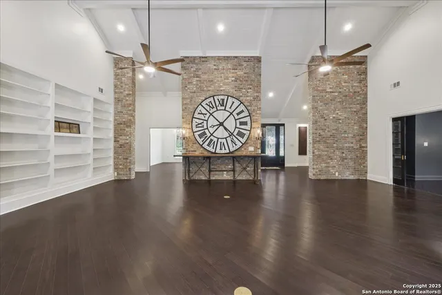 an empty room with wooden floor chandelier and windows