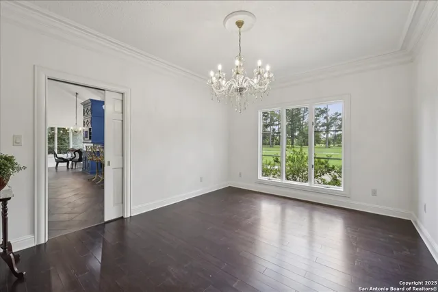 a view of a livingroom with wooden floor a chandelier and windows