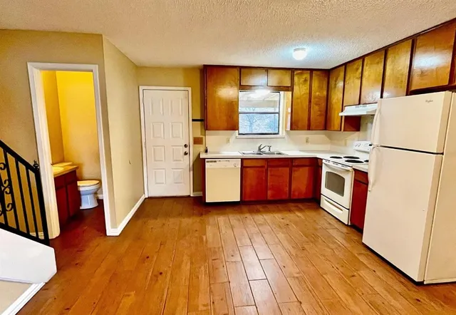 a kitchen with stainless steel appliances granite countertop wooden floors a stove and a refrigerator