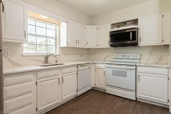 a kitchen with white cabinets appliances and a sink
