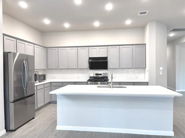 a kitchen with kitchen island granite countertop a sink appliances and cabinets