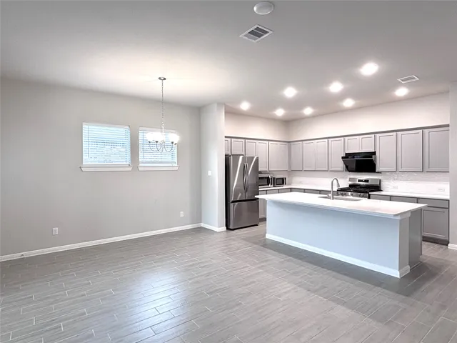 a kitchen with stainless steel appliances kitchen island sink refrigerator and cabinets
