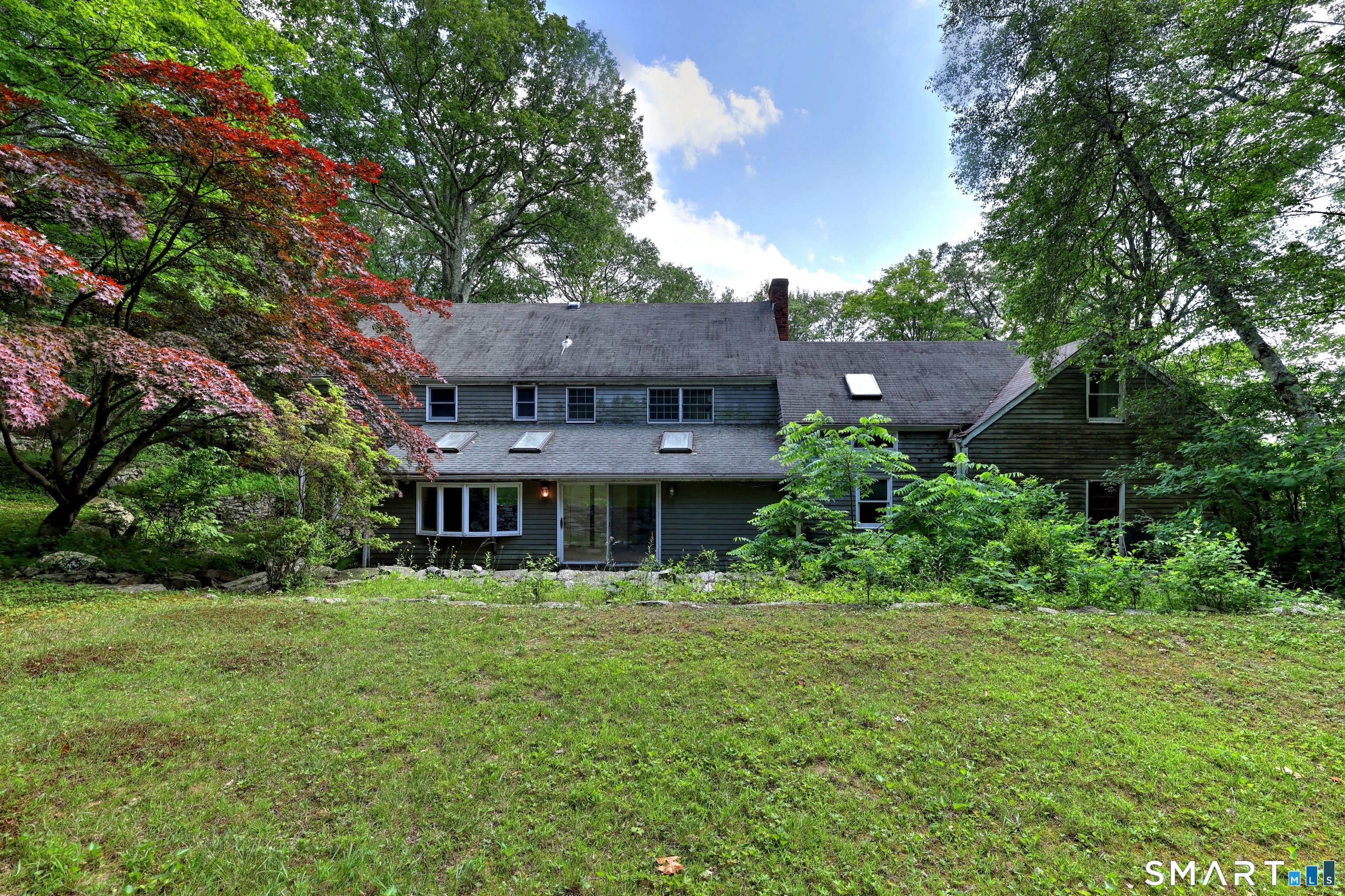 a view of a house with a big yard plants and large trees