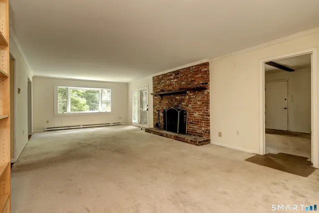 an empty room with windows and fireplace