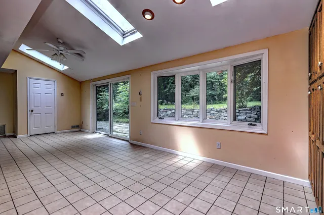 a view of an empty room with window and chandelier fan