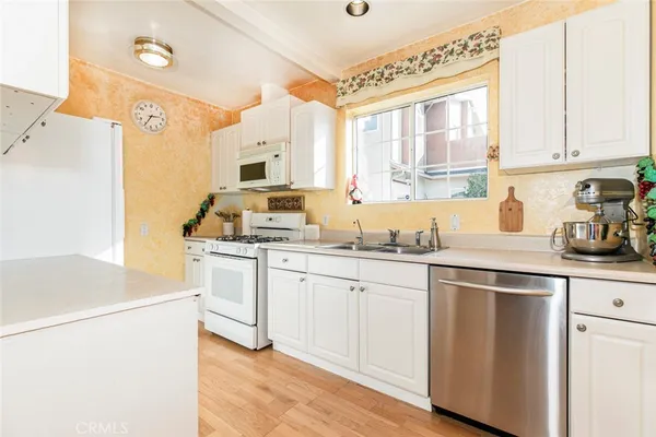 a kitchen with granite countertop white cabinets and white appliances