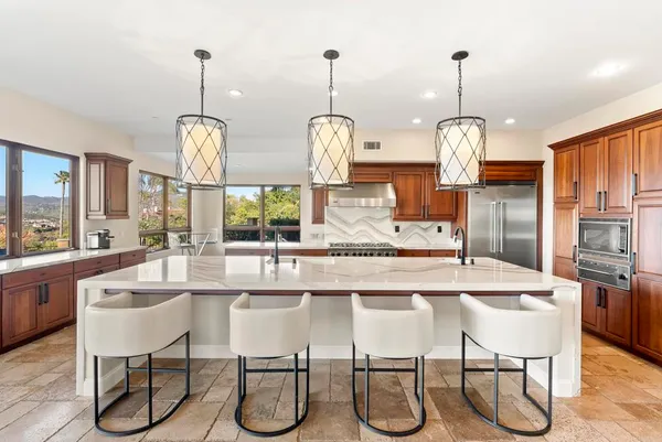 a kitchen with stainless steel appliances kitchen island granite countertop a stove a refrigerator a oven a dining table and chairs with wooden floor