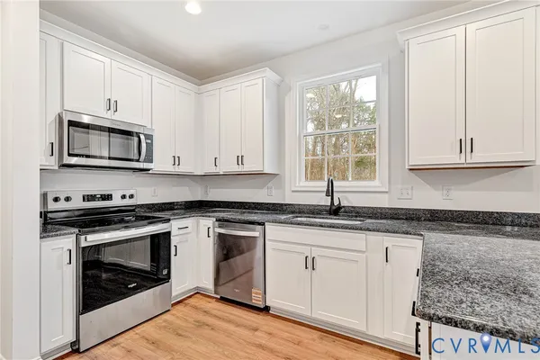 a kitchen with granite countertop wooden cabinets appliances and a window