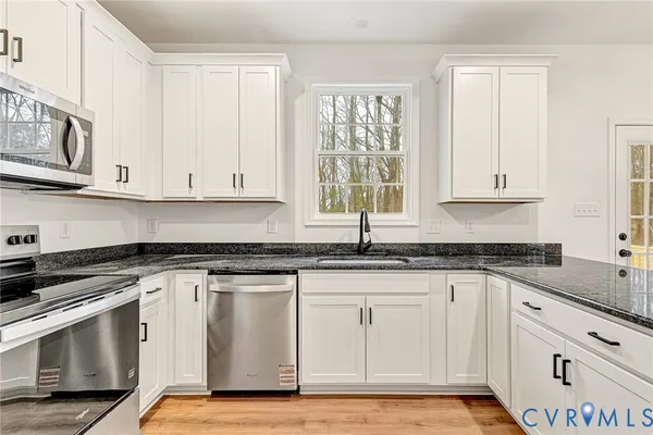 a white kitchen with granite countertop white cabinets and a stainless steel appliances