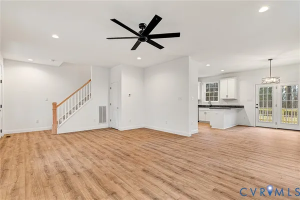 a view of empty room with wooden floor and ceiling fan