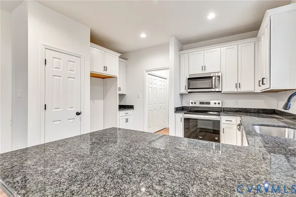 a kitchen with stainless steel appliances granite countertop a stove a sink and a refrigerator