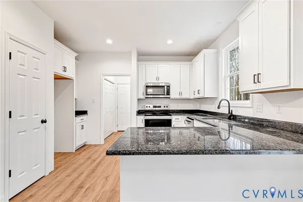 a kitchen with stainless steel appliances granite countertop a sink a stove a refrigerator a microwave and cabinets