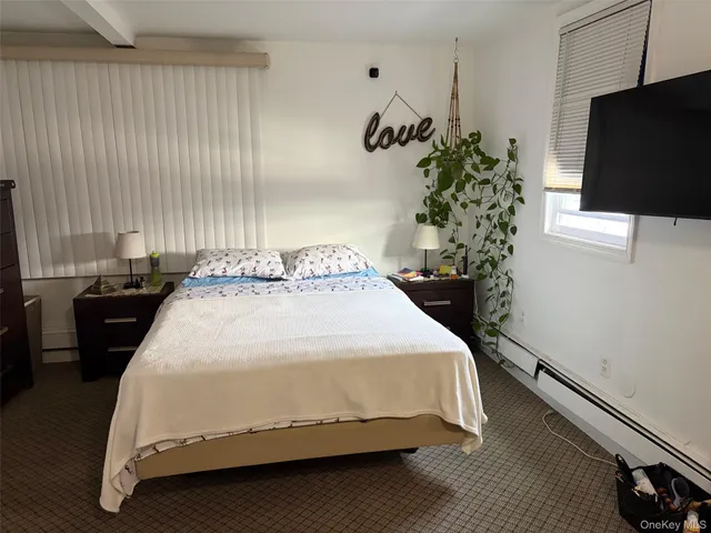 a bedroom with a bed and a flat tv screen on the dresser
