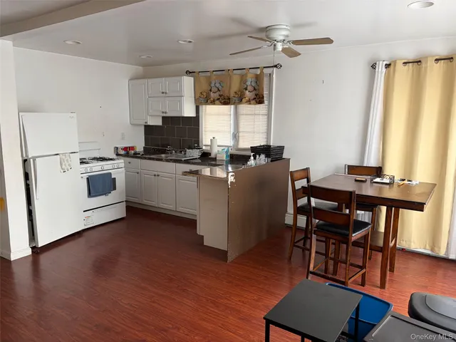 a kitchen with stainless steel appliances granite countertop a stove top oven a refrigerator a dining table and chairs with wooden floor