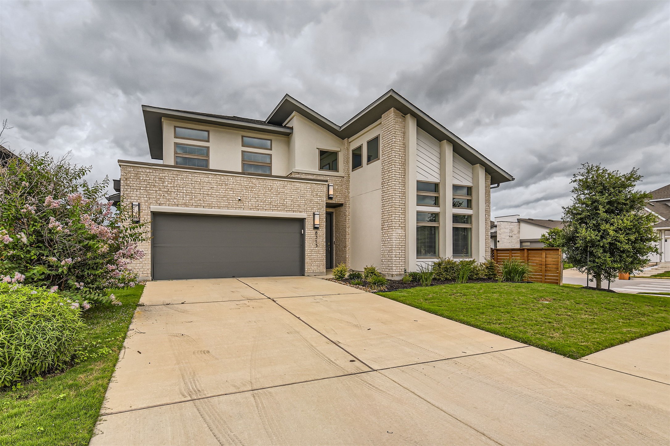 8313 Spire View Austin, TX 78744 - Photo 2 of 33 Modern facade with mixed materials, a dark garage door, and neat landscaping creates inviting curb appeal.