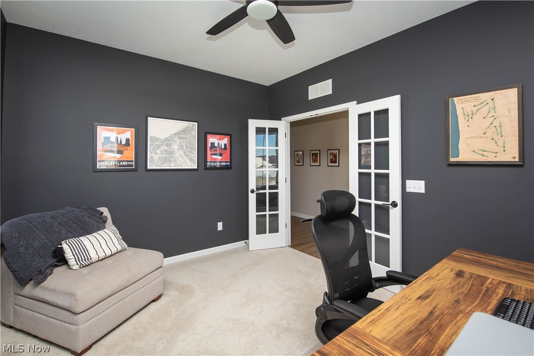 Carpeted home office featuring french doors and a ceiling fan