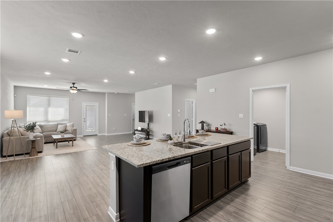 1925 Viva Road Bryan, TX 77807 - Photo 22 of 24 a large kitchen with kitchen island a sink dishwasher a dining table and chairs with wooden floor