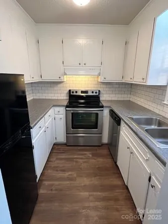 a kitchen with granite countertop white cabinets and stainless steel appliances