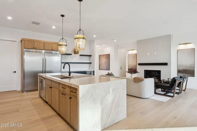 a kitchen with stainless steel appliances granite countertop a stove top oven a sink refrigerator and a fireplace with wooden floor