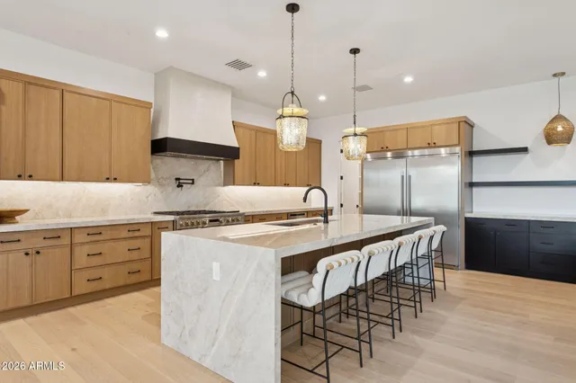 a kitchen with stainless steel appliances granite countertop a stove a sink a oven a dining table and chairs with wooden floor