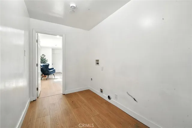a view of a hallway with wooden floor and a bathroom