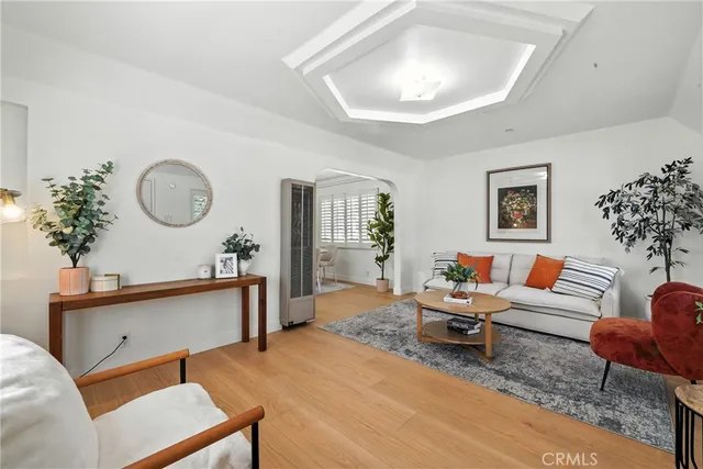 a living room with furniture a lamp paintings and a wooden floor