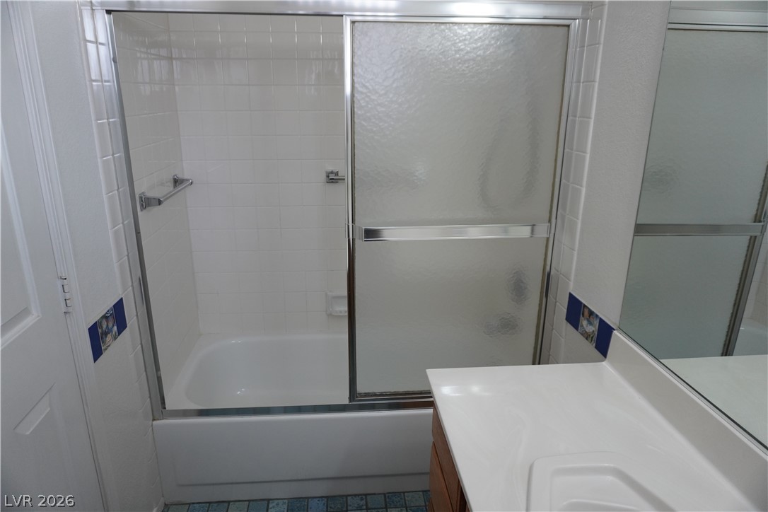 8328 Del Rey Avenue Las Vegas, NV 89117 - Photo 30 of 38 White subway tile surrounds a sleek glass-enclosed shower over a tub.