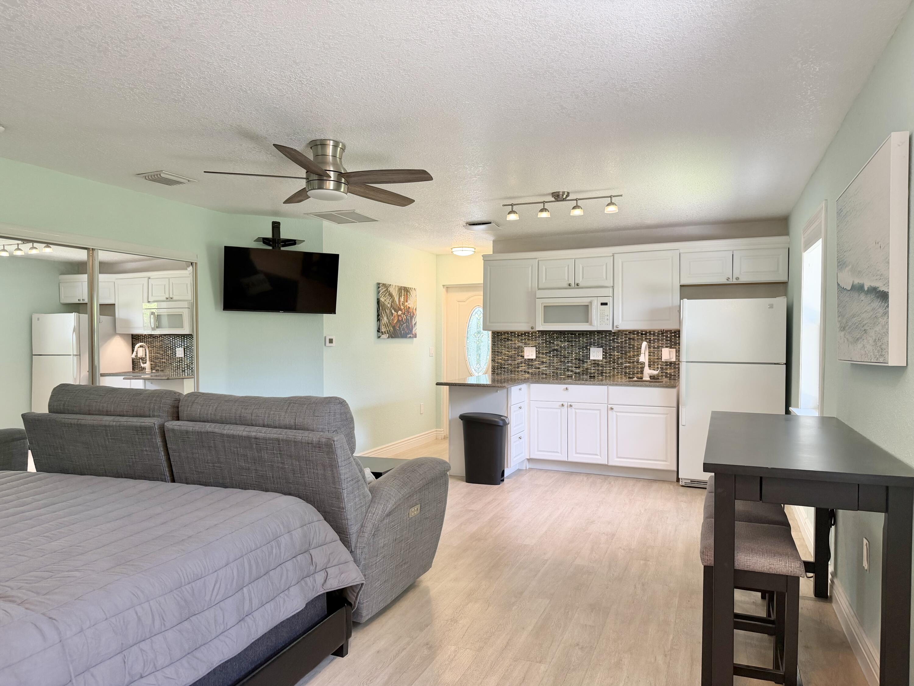 6100 Francis Street, Unit B Jupiter, FL 33458 - Photo 3 of 19 a large bedroom with a large bed a flat screen tv and a large window