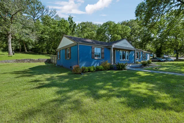 a view of a house with a big yard plants and large trees