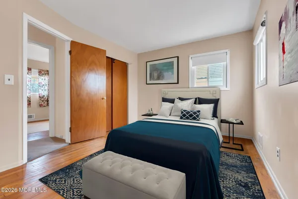 a view of an empty room with wooden floor and a bathroom