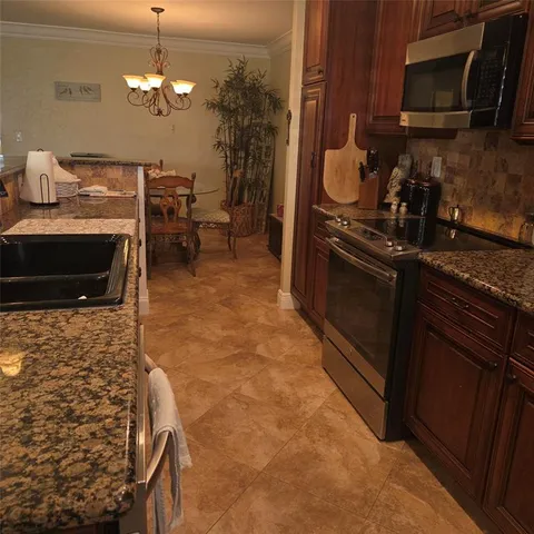 a kitchen with granite countertop a stove a microwave a dining table and chairs