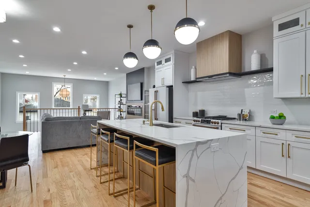 a kitchen with stainless steel appliances granite countertop a sink a stove a oven a dining table and chairs with wooden floor