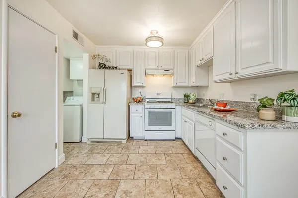 a kitchen with granite countertop white cabinets and white appliances
