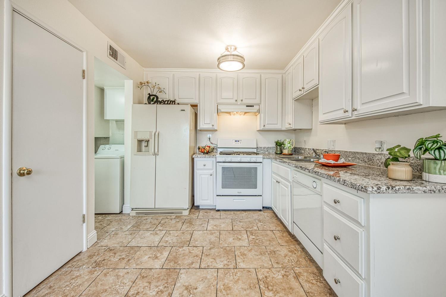 6656 North 3rd Street Fresno, CA 93710 - Photo 11 of 31 a kitchen with granite countertop a refrigerator a sink dishwasher and white cabinets with wooden floor
