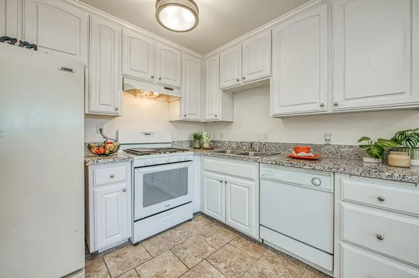 a kitchen with granite countertop white cabinets and sink