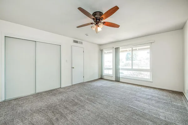 an empty room with a window and a ceiling fan