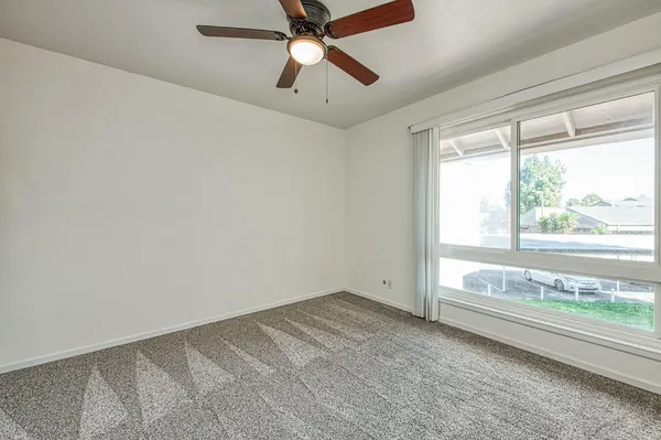a view of an empty room with window and a ceiling fan