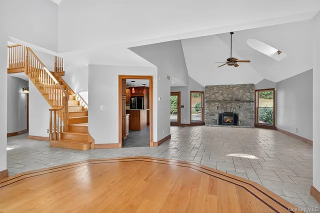 a view of an empty room with wooden floor fireplace and a window