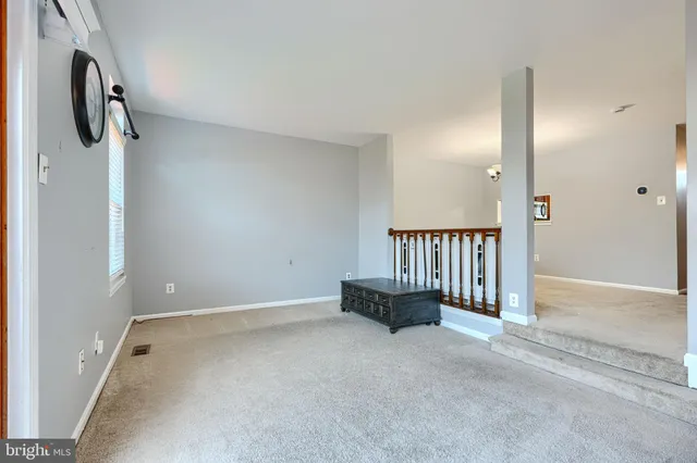 a view of an empty room with a window and a kitchen