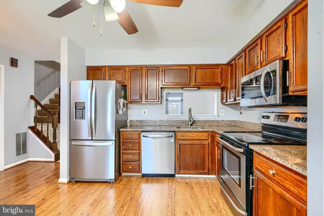 a kitchen with stainless steel appliances granite countertop a refrigerator a stove top oven a sink and dishwasher with wooden floor