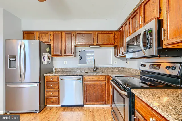 a kitchen with stainless steel appliances granite countertop a refrigerator a stove a sink and a microwave