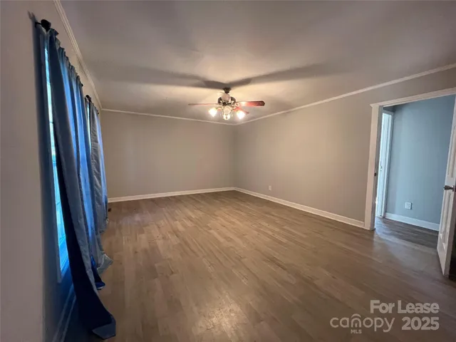 an empty room with wooden floor and chandelier fan