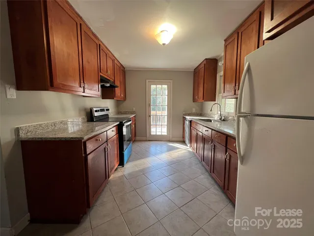 a kitchen with stainless steel appliances granite countertop a refrigerator a sink dishwasher a stove top oven a refrigerator and cabinets