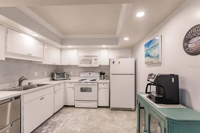 a kitchen with stainless steel appliances a sink a stove a refrigerator cabinets and a window