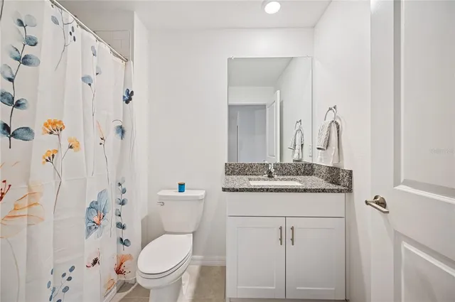 a bathroom with a granite countertop toilet a sink and a mirror