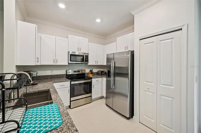 a kitchen with granite countertop stainless steel appliances a stove a microwave a refrigerator and cabinets